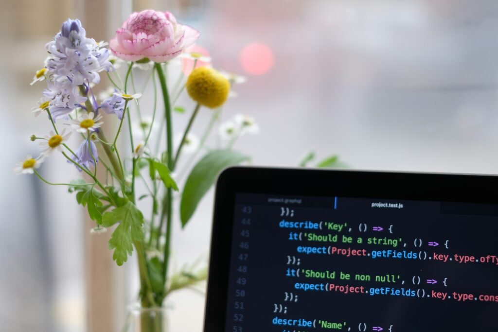 black laptop computer turned on near yellow flowers